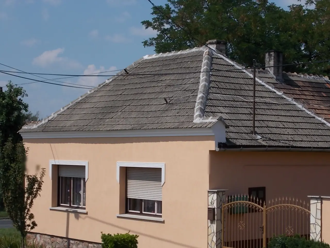 Sátortetős kockaház vakolt homlokzattal, nyári napsütésben